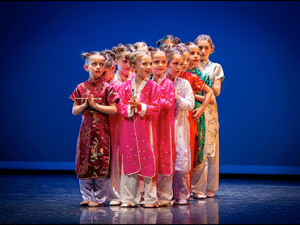 Groupe d’enfants en costume traditionnel sur scène pendant un spectacle de danse